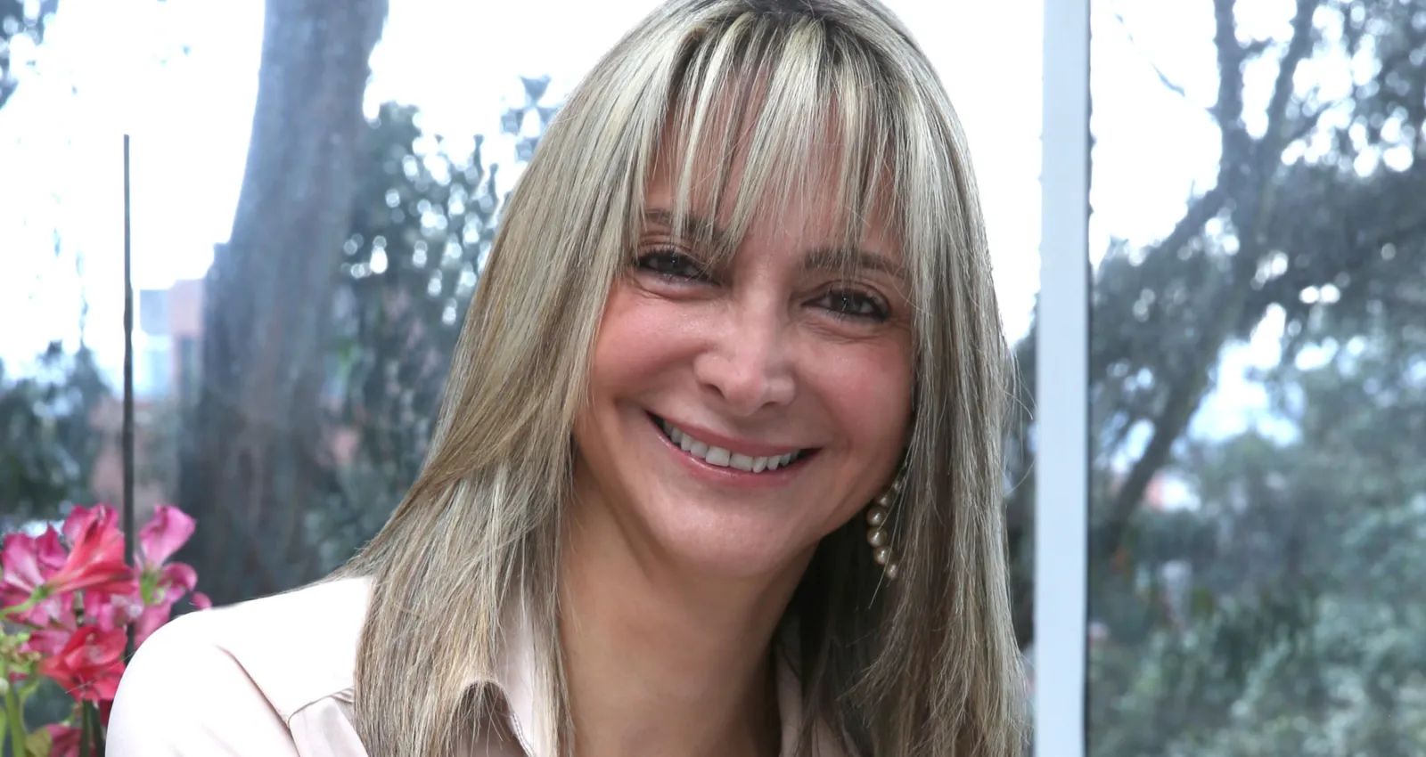 Mujer con cabello rubio sonriendo a la cámara