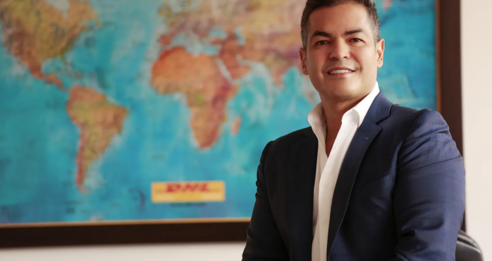 foto de un señor sonriendo a la cámara con un mapa de fondo