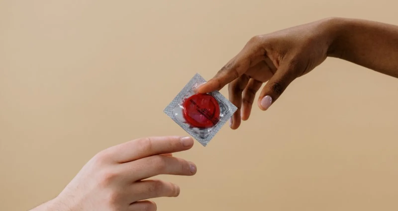 Foto de dos manos compartiendo un condón