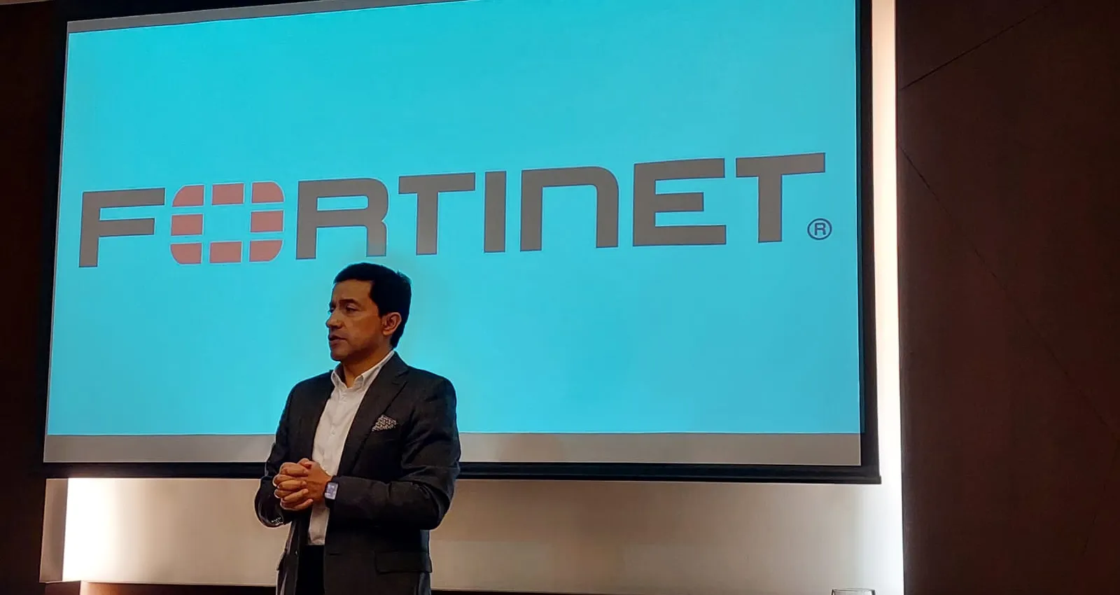foto de un hombre exponiendo un tema frente a una pantalla que dice Fortinet