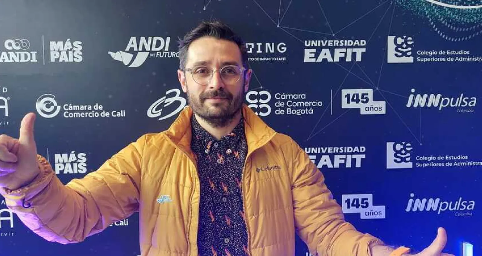 Foto de Andrés Raigosa, hombre con camiseta negra y chaqueta amarilla