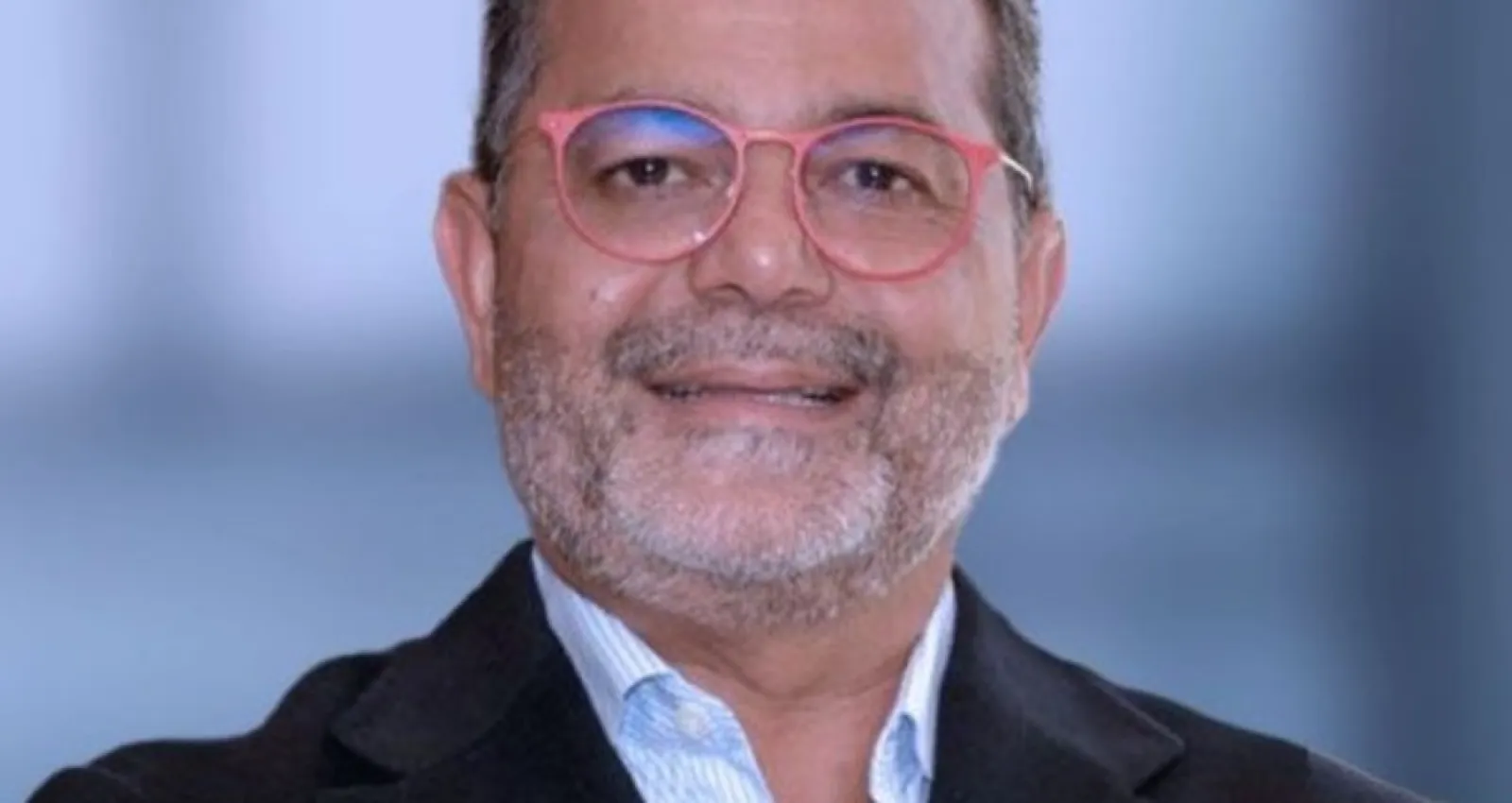 Foto de un profesional con gafas rojas mirando a la cámara