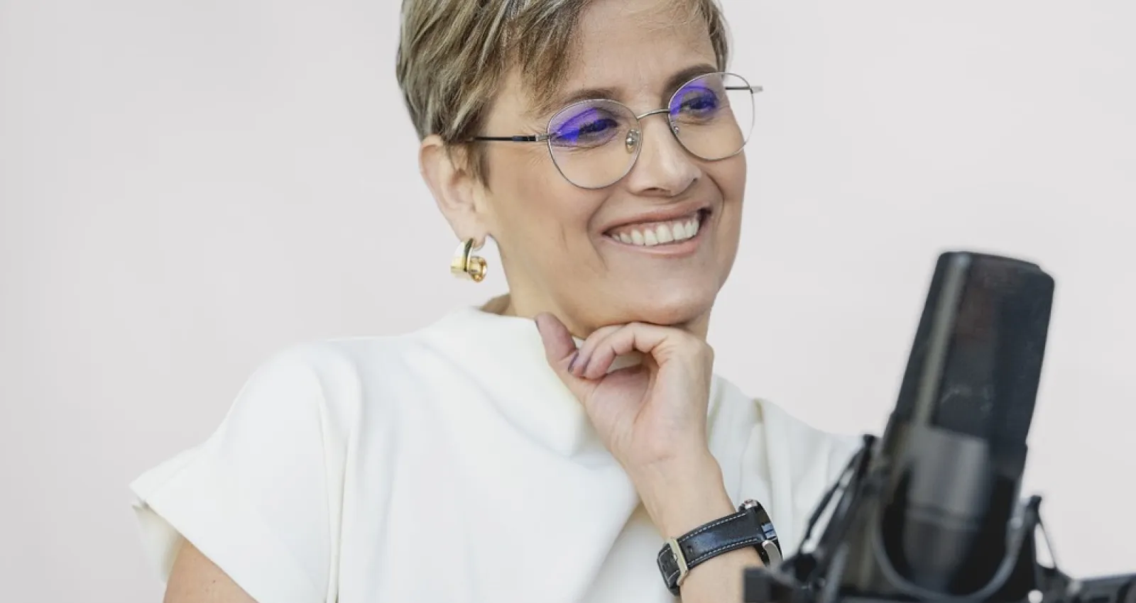 Foto de Patricia Velásquez, una mujer sonriente con un micrófono de frente