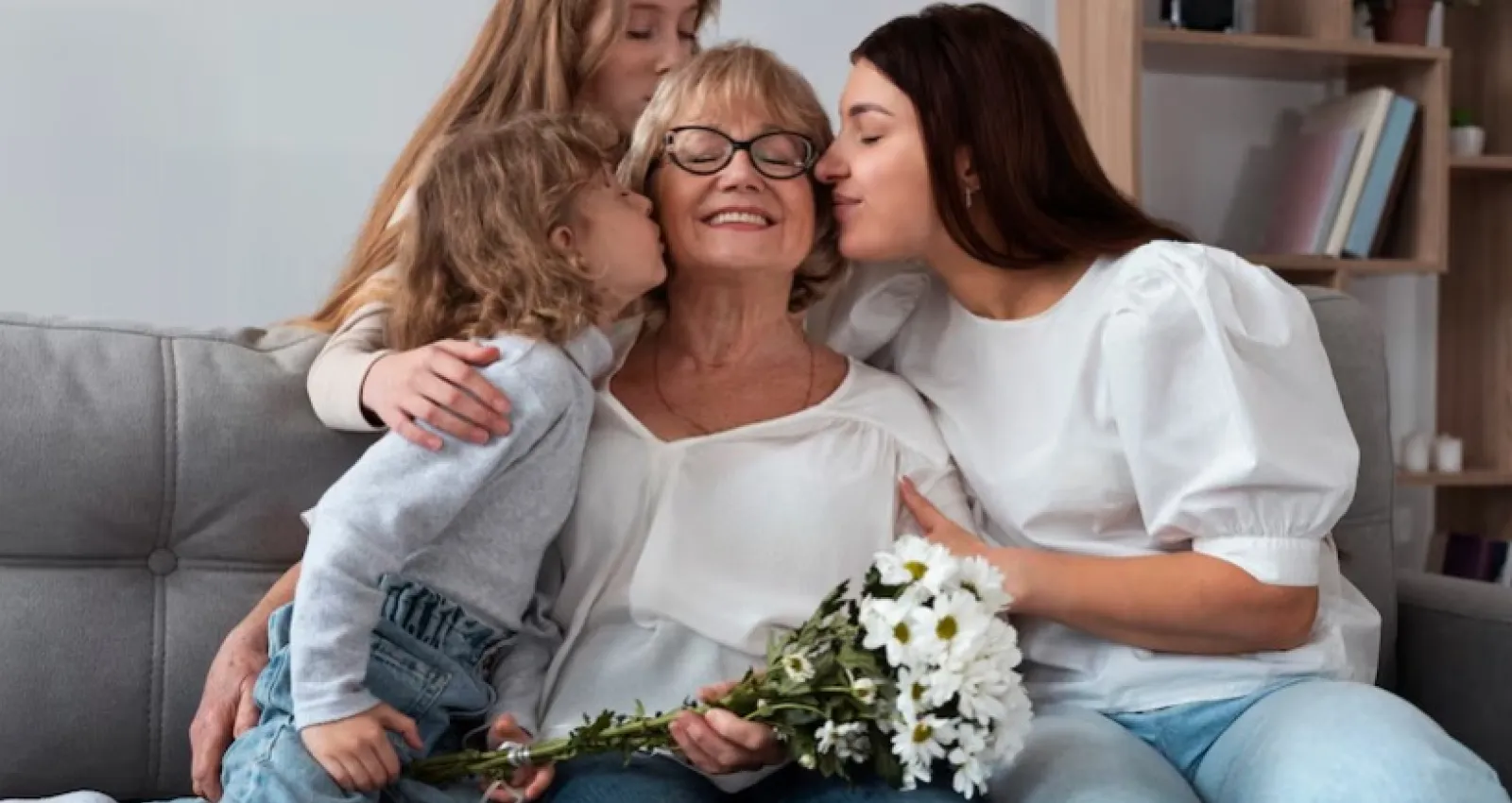 Foto de dos hijas besajndo a su mamá en la mejilla