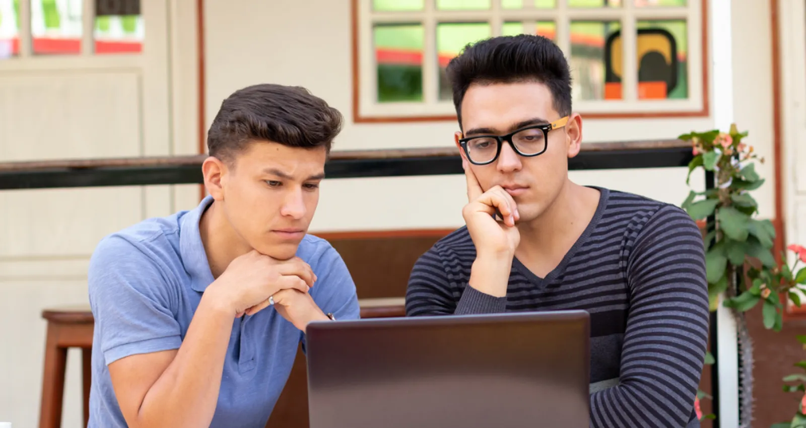 Foto de dos jóvenes mirando el computador mientras piensan