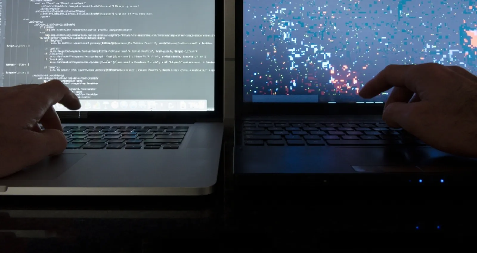 Foto de dos manos escribiendo sobre dos computadores portátiles