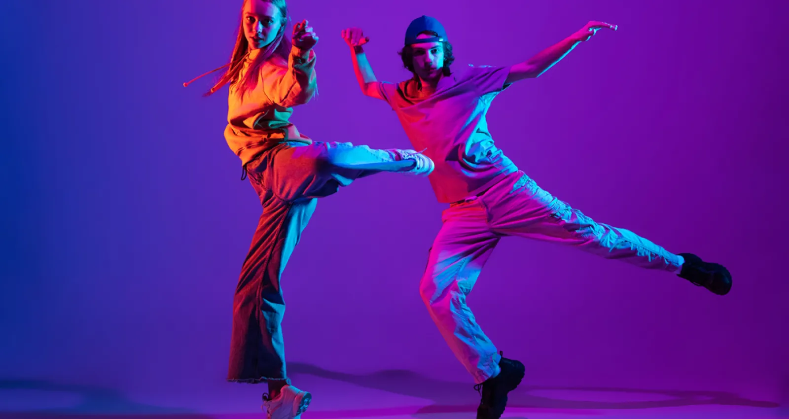Foto de dos personas bailando con un fondo morado 