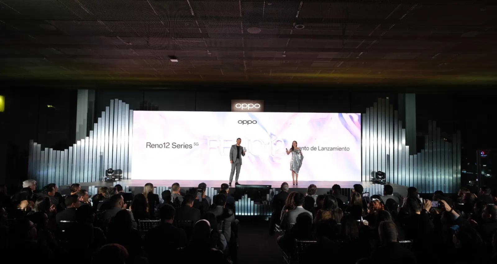 Foto de dos personas presentando frente a una gran pantalla de luz