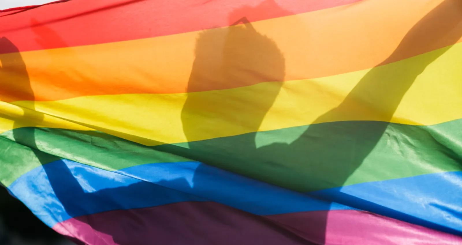 Foto de la silueta de un hombre detrás de una bandera inclusiva
