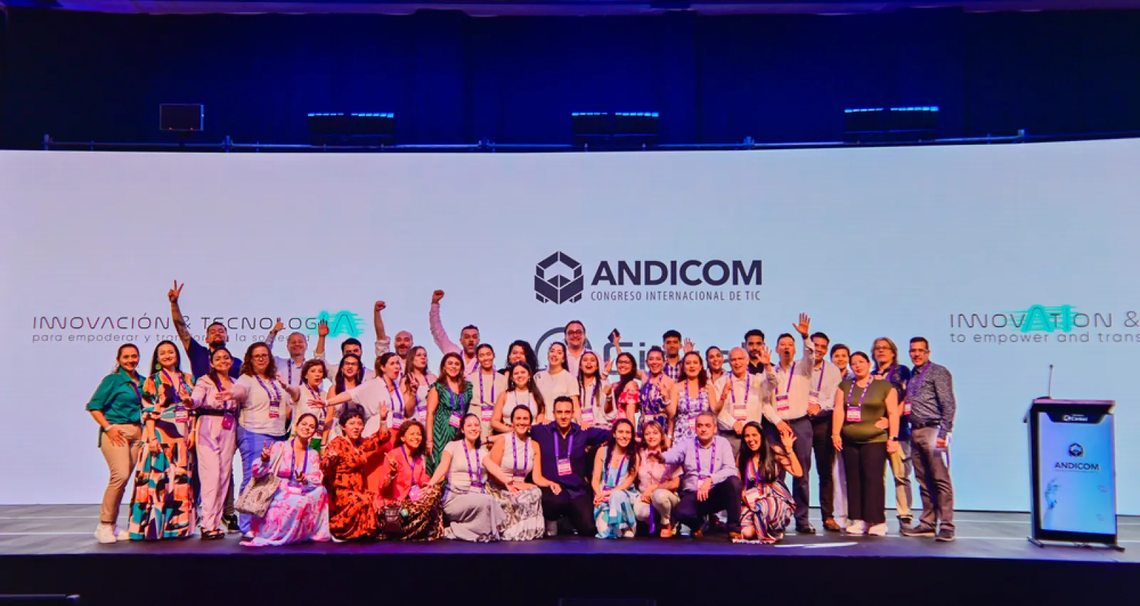 Foto de más de 10 personas reunidas frente a la cámara y un fondo de Andicom en el fondo