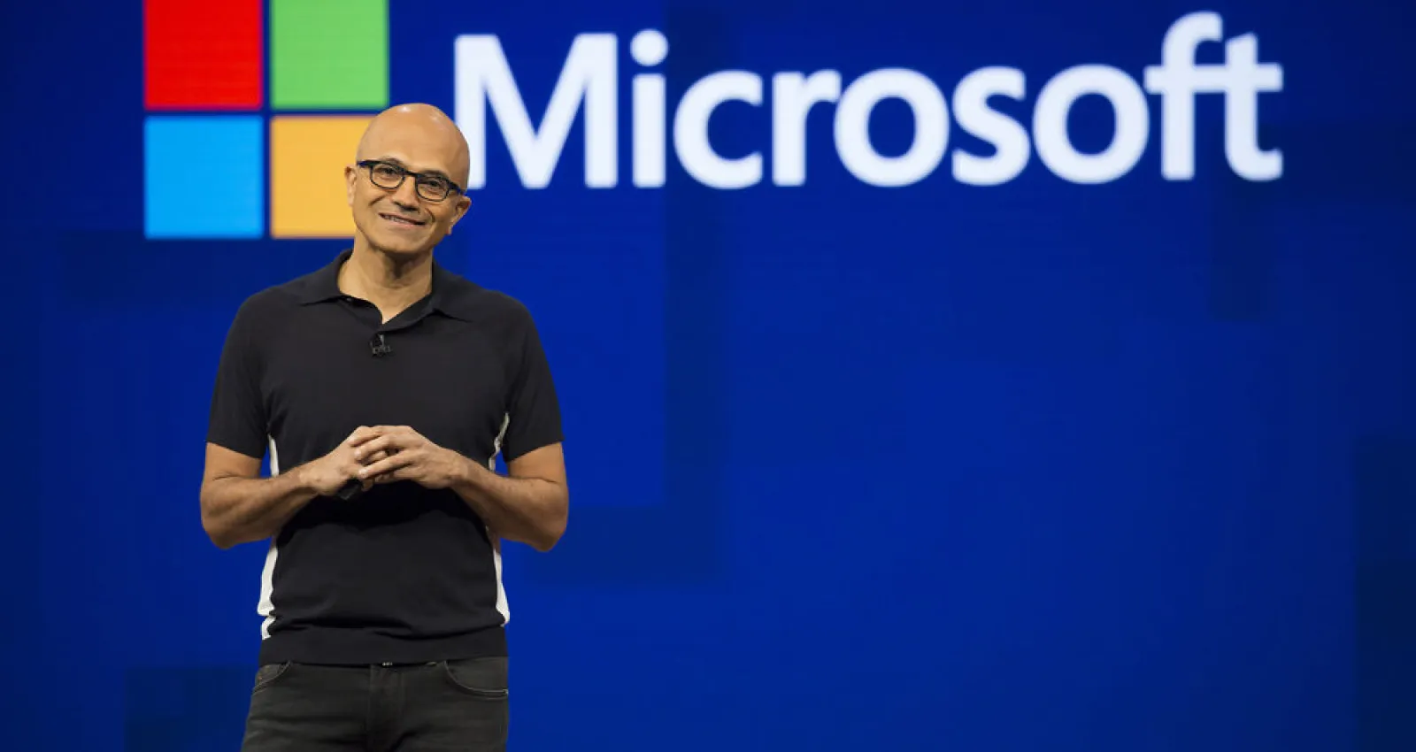 Foto de un señor explicando un tema frente  un fondo de Microsoft