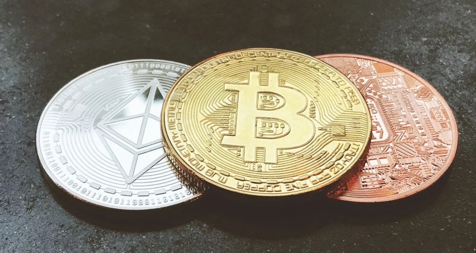 Foto de tres criptomonedas de diferente color