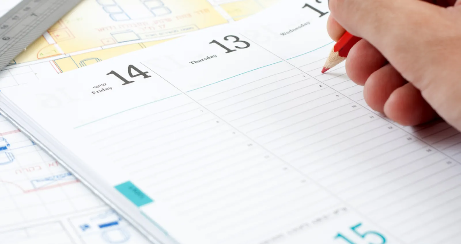 Foto de un calendario genérico con una mano encima y una persona escribiendo sobre él