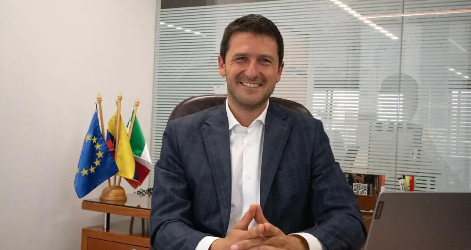 Foto de un dilomático jóven sentado mirando a la cámara