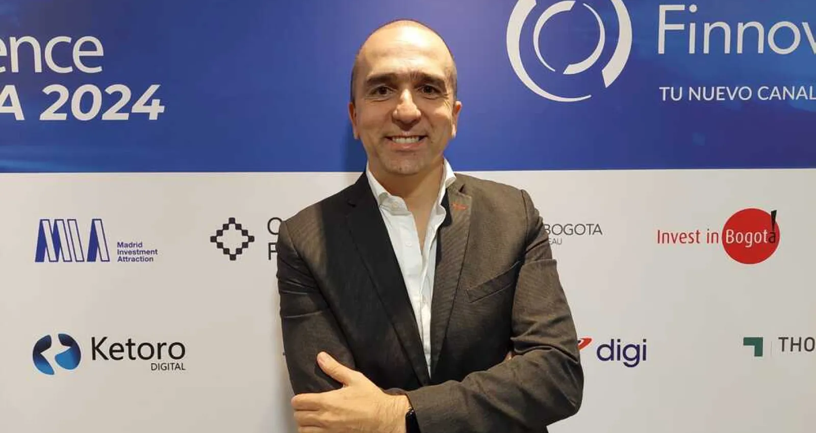 Foto de un ejecutivo mirando a la cámara con un fondo d eun evento promocional