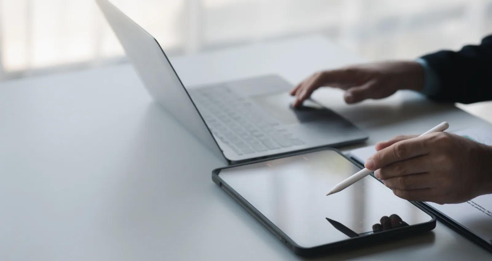 Foto de un empresario con un computador en un lado de la mesa y una tablet en el otro