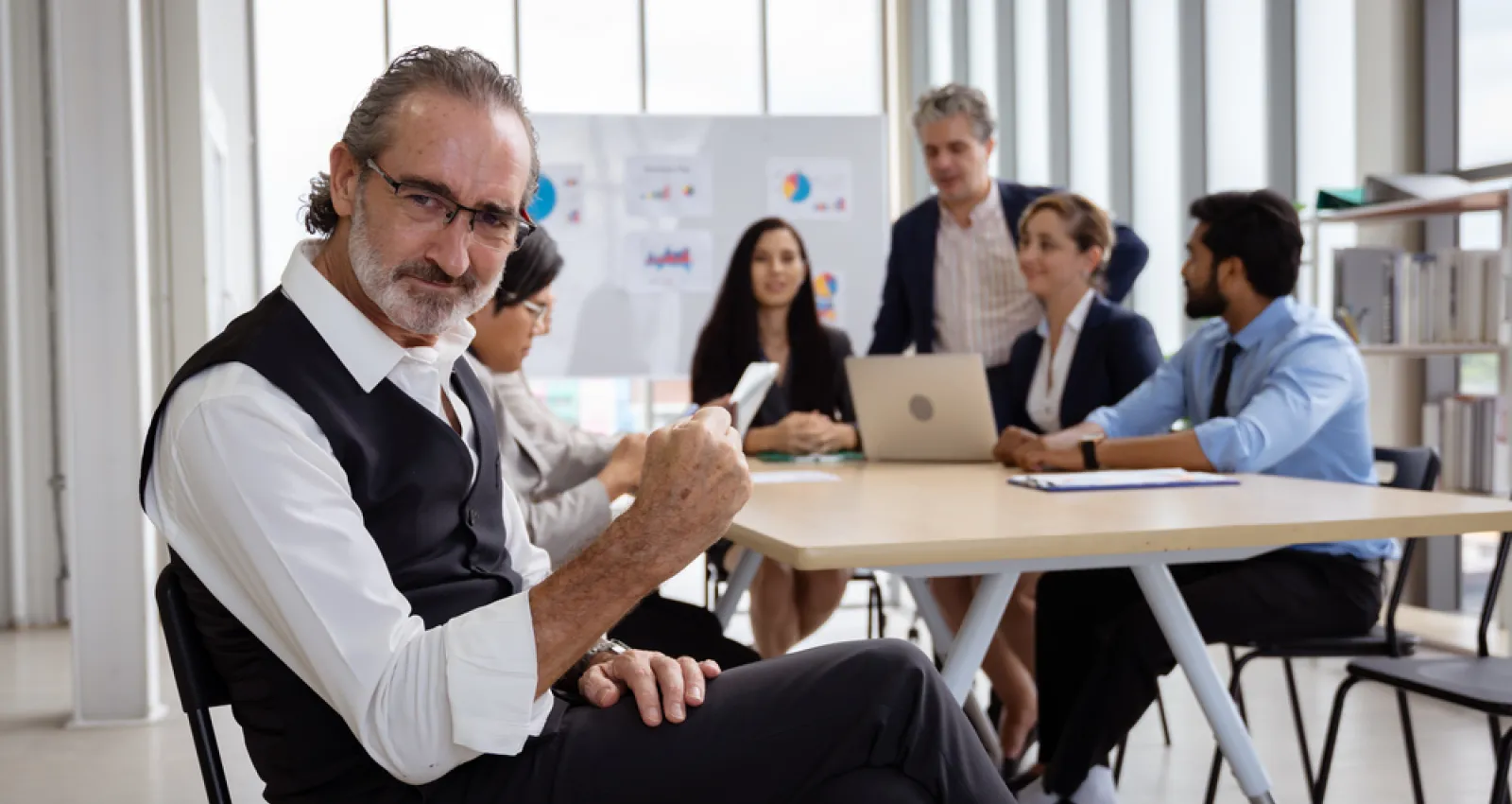 Foto de un empresario mirando a la cámara con personal detras