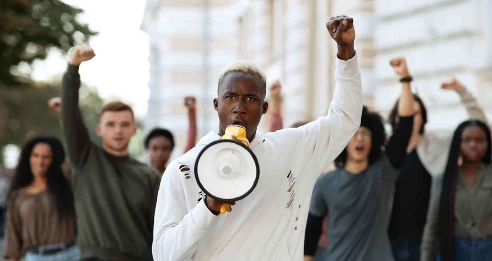 Foto de un hombre afroamericano alzando la mano con un megáfono en mano
