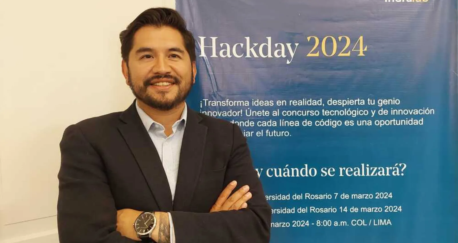 Foto de un hombre con elo negro y blazer mirando a la cámara
