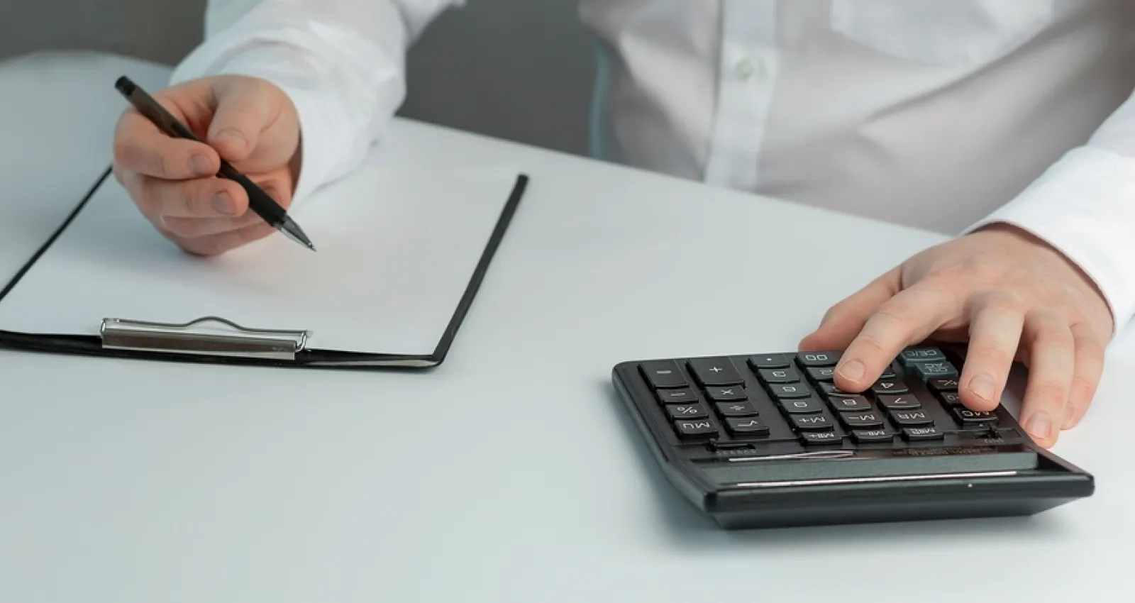 Foto de un hombre con una calculadora y una hoja de papel