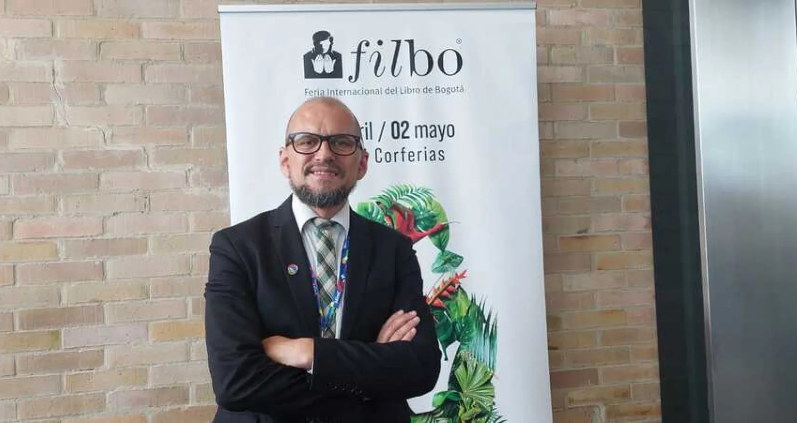 Foto de un hombre cruzado de brasil con barba y gafas negras mirando a la cámara