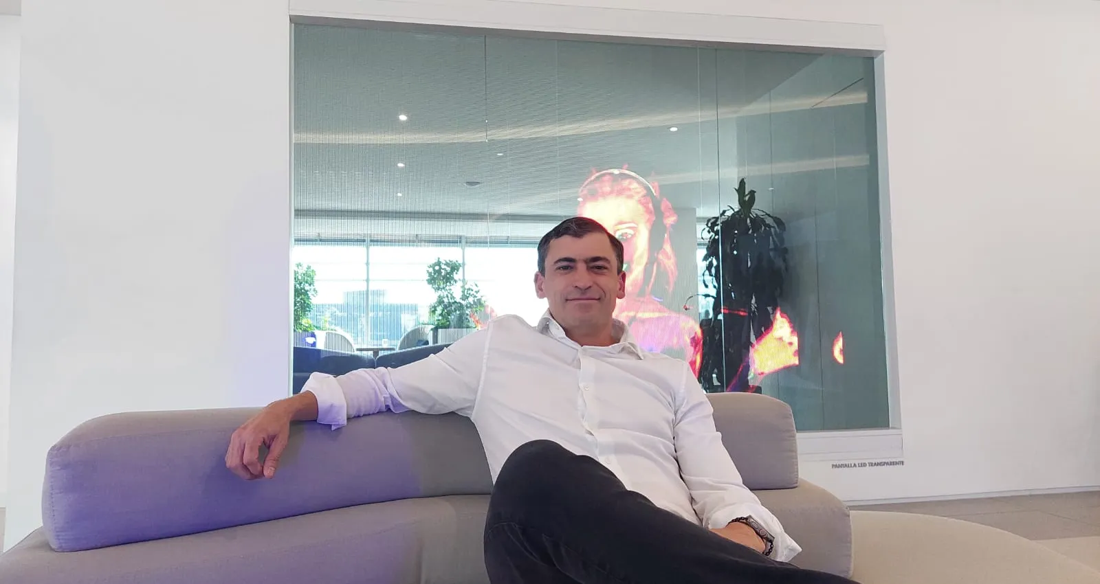 Foto de un hombre sentado sobre un sofa mirando la cámara con la pierna cruzada