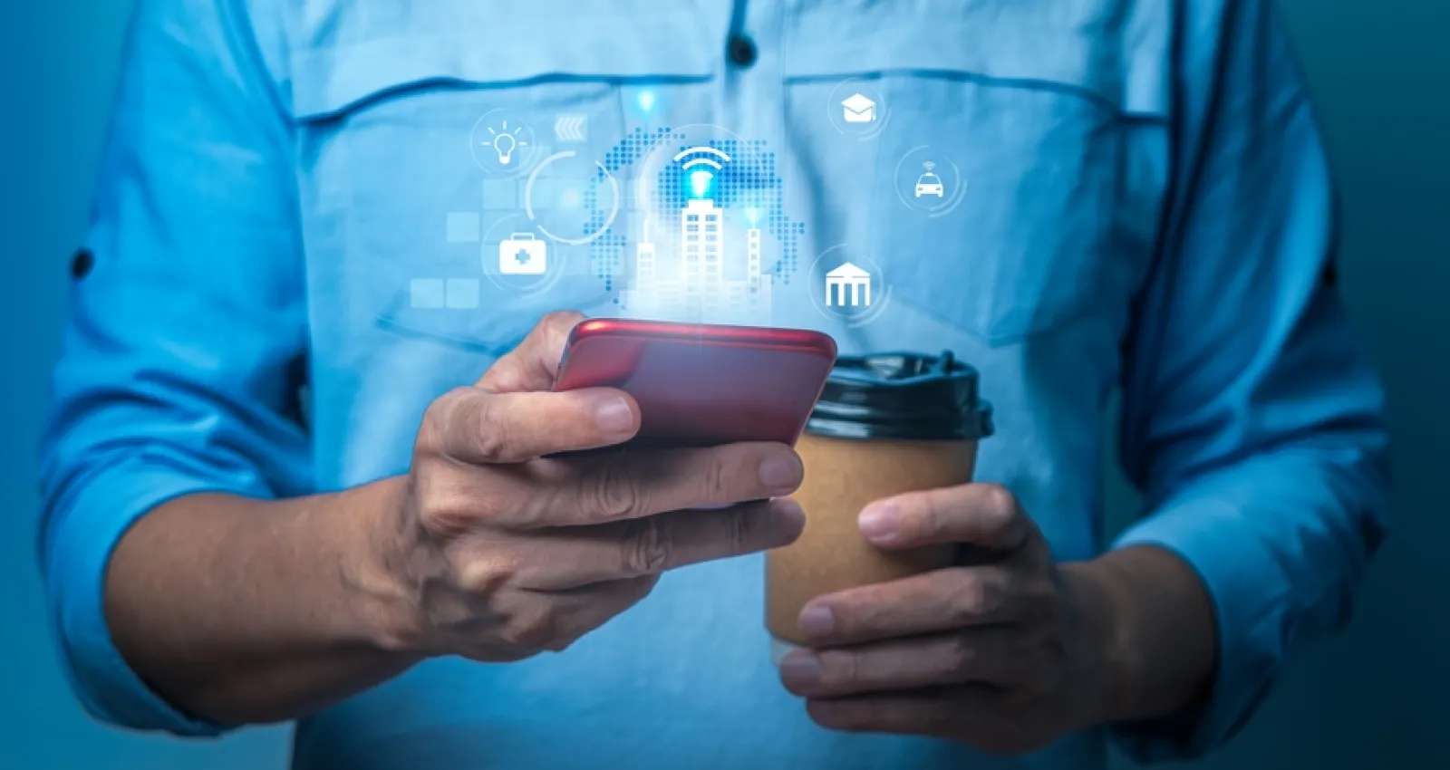 Foto de un hombre utilizando su celular en una mano y con un café en la otra