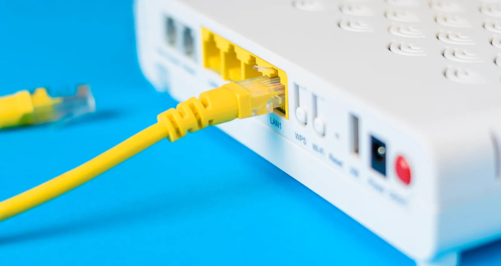 Foto de un modem blanco con cableado amarillo y fondo azul