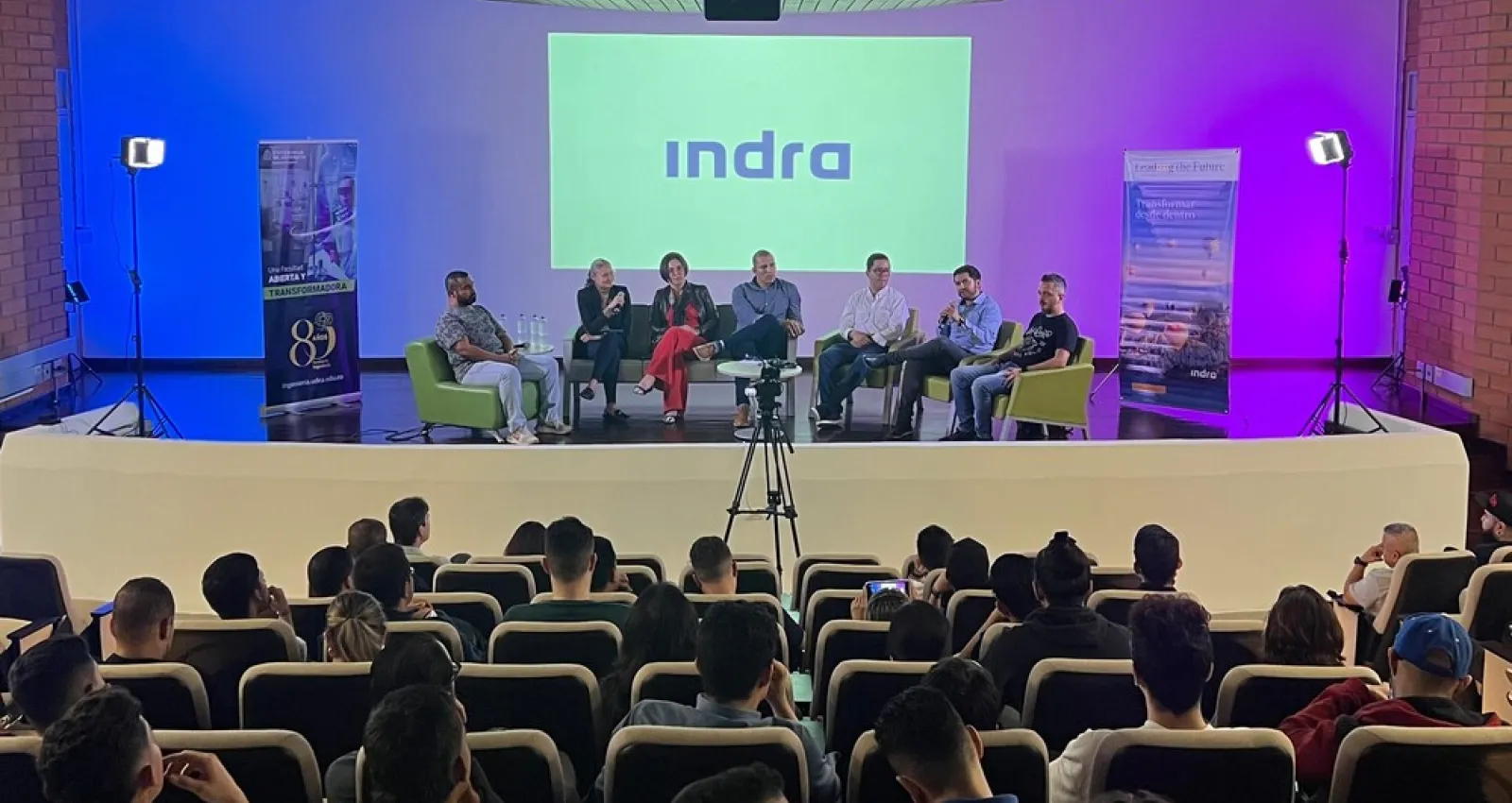 Foto de un panel con varias personas sentadas conversando frente a un auditorio