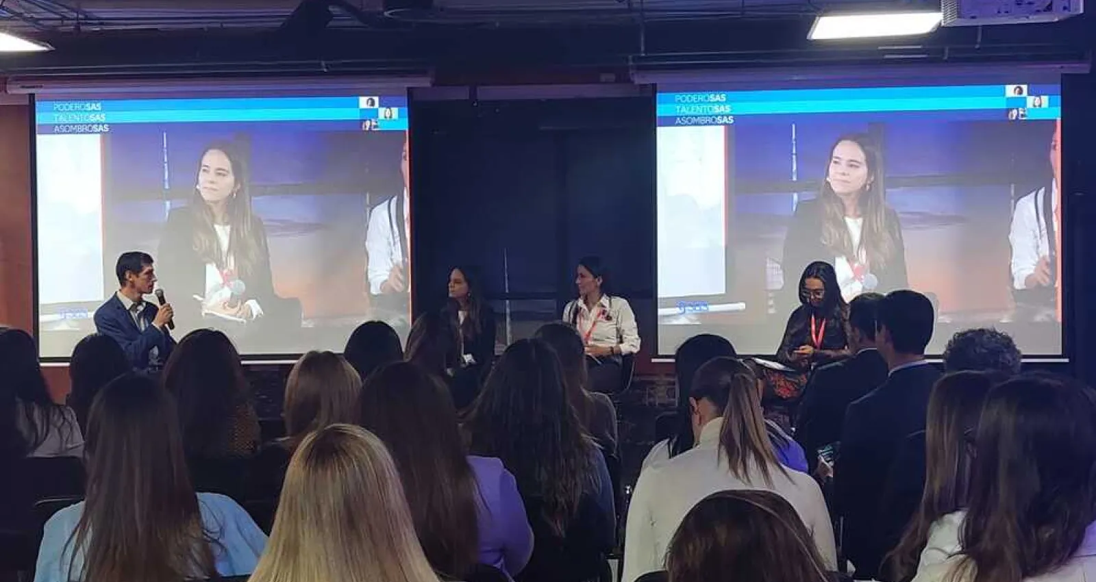 Foto de un salón lleno de personas con mujeres panelistas