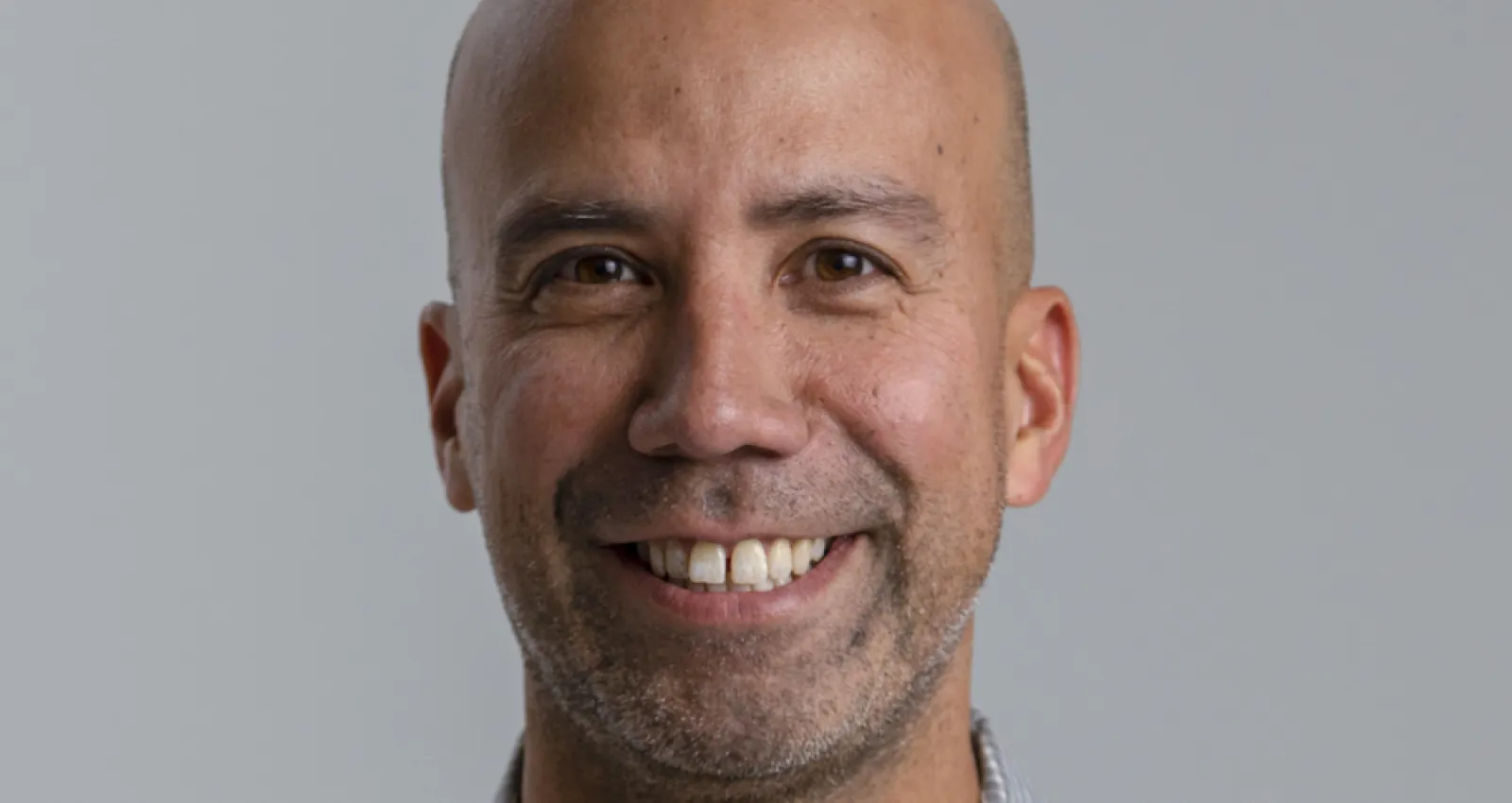 Foto de un hombre sonriente con un fondo gris