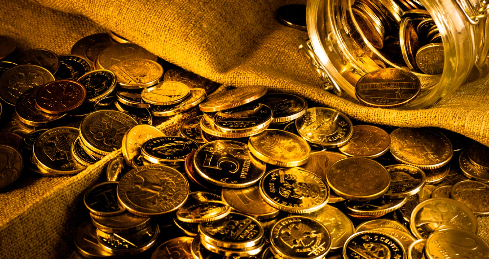 Foto de varias monedas de oro sobre una bolsa de oro