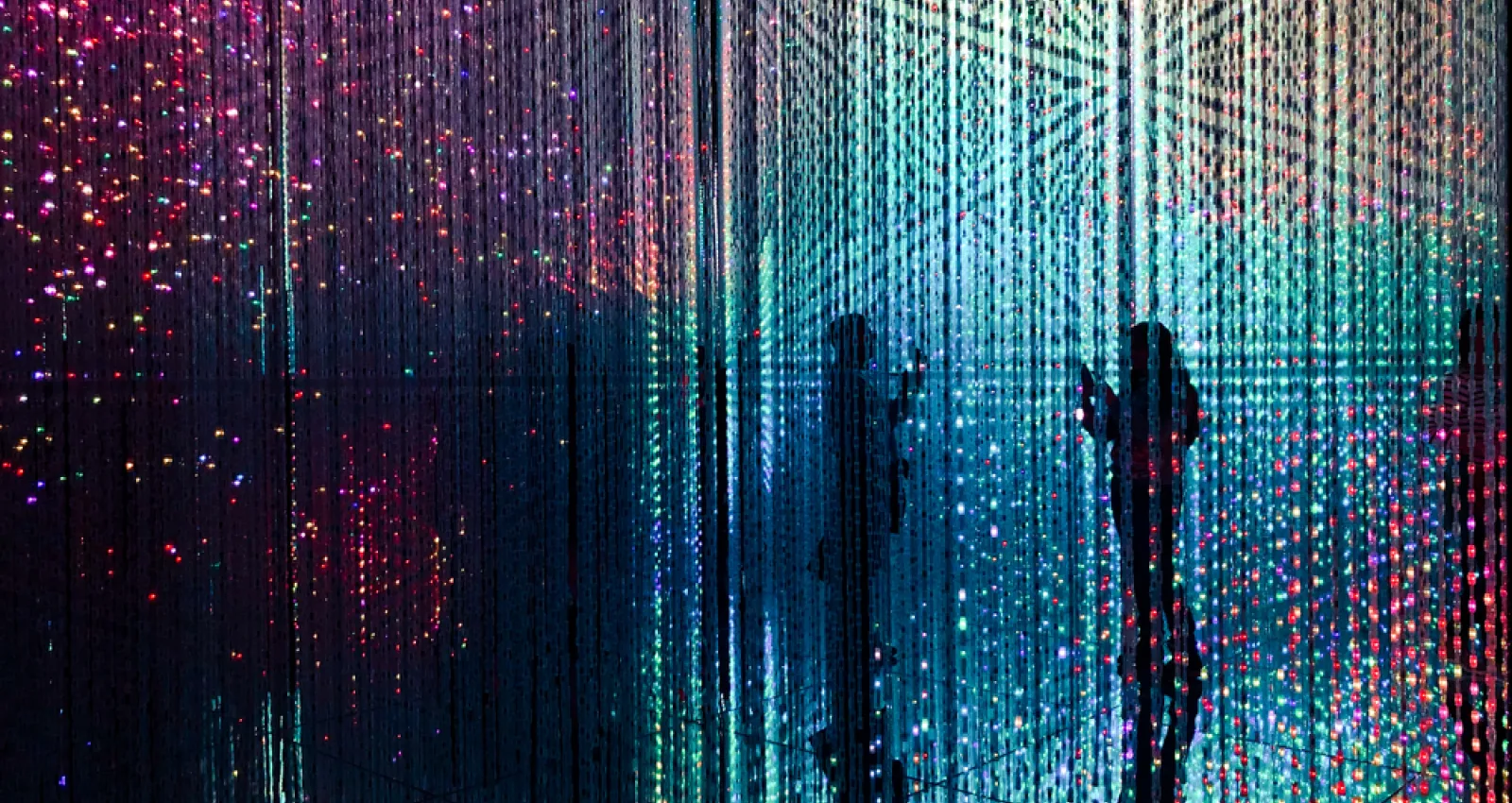 Foto de una exhibición de arte con varias luces y dos siluetas de fondo