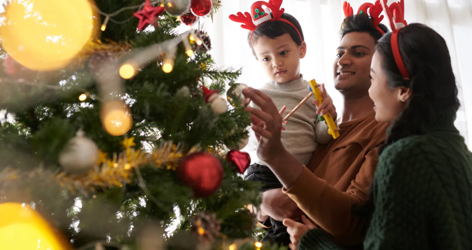 Foto de una familia poniendo objetos en un árbol de navidad