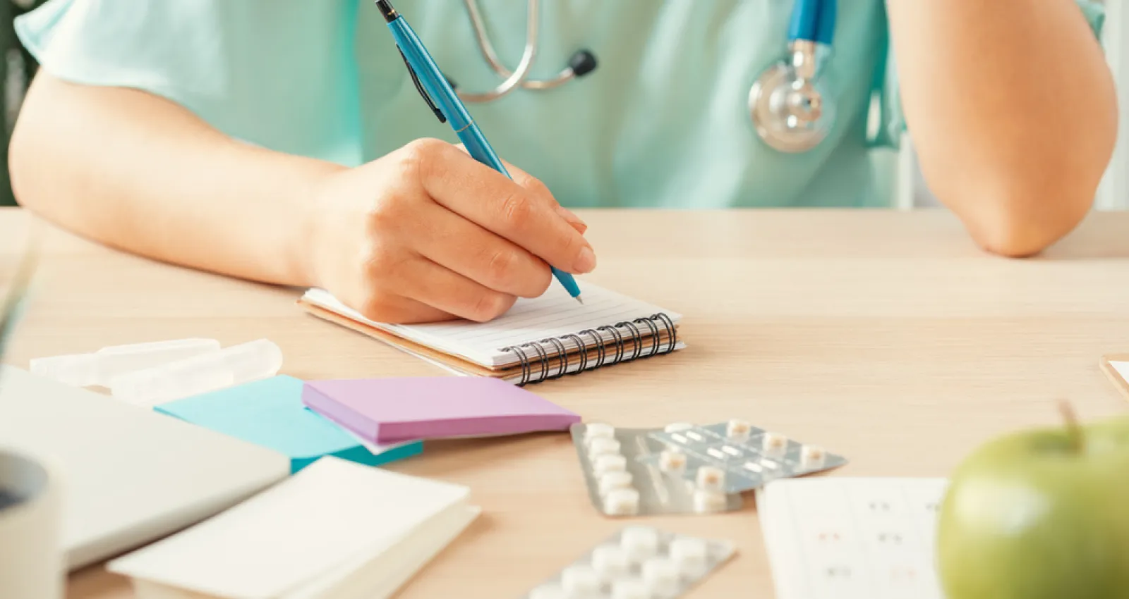 Foto de una médica escribiendo sobre una hoja de papel