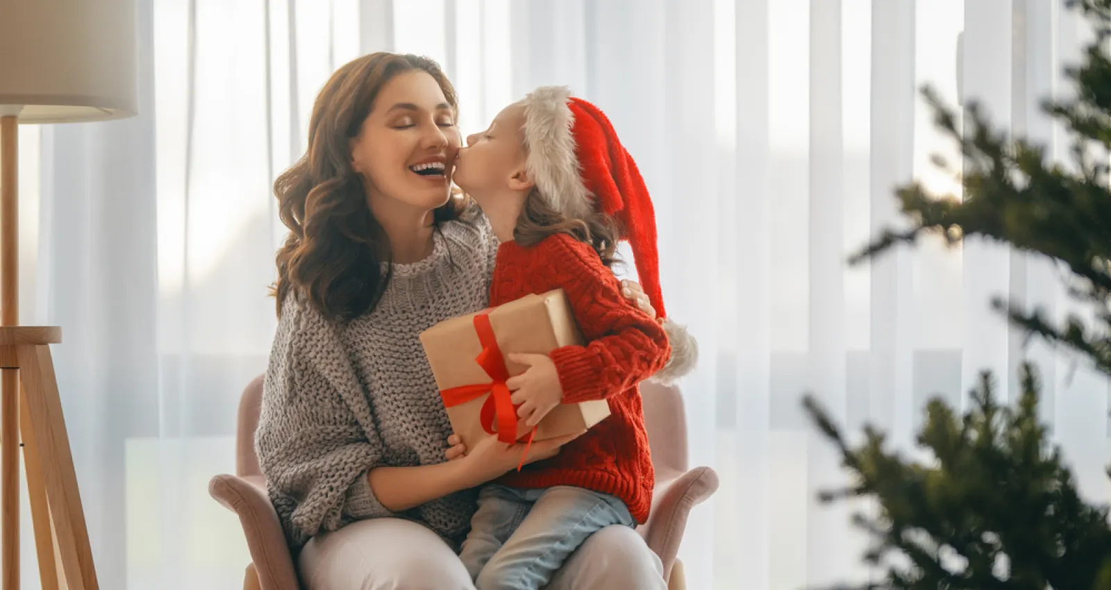 Foto de una mandre y su hija sentadas con detalles de navidad