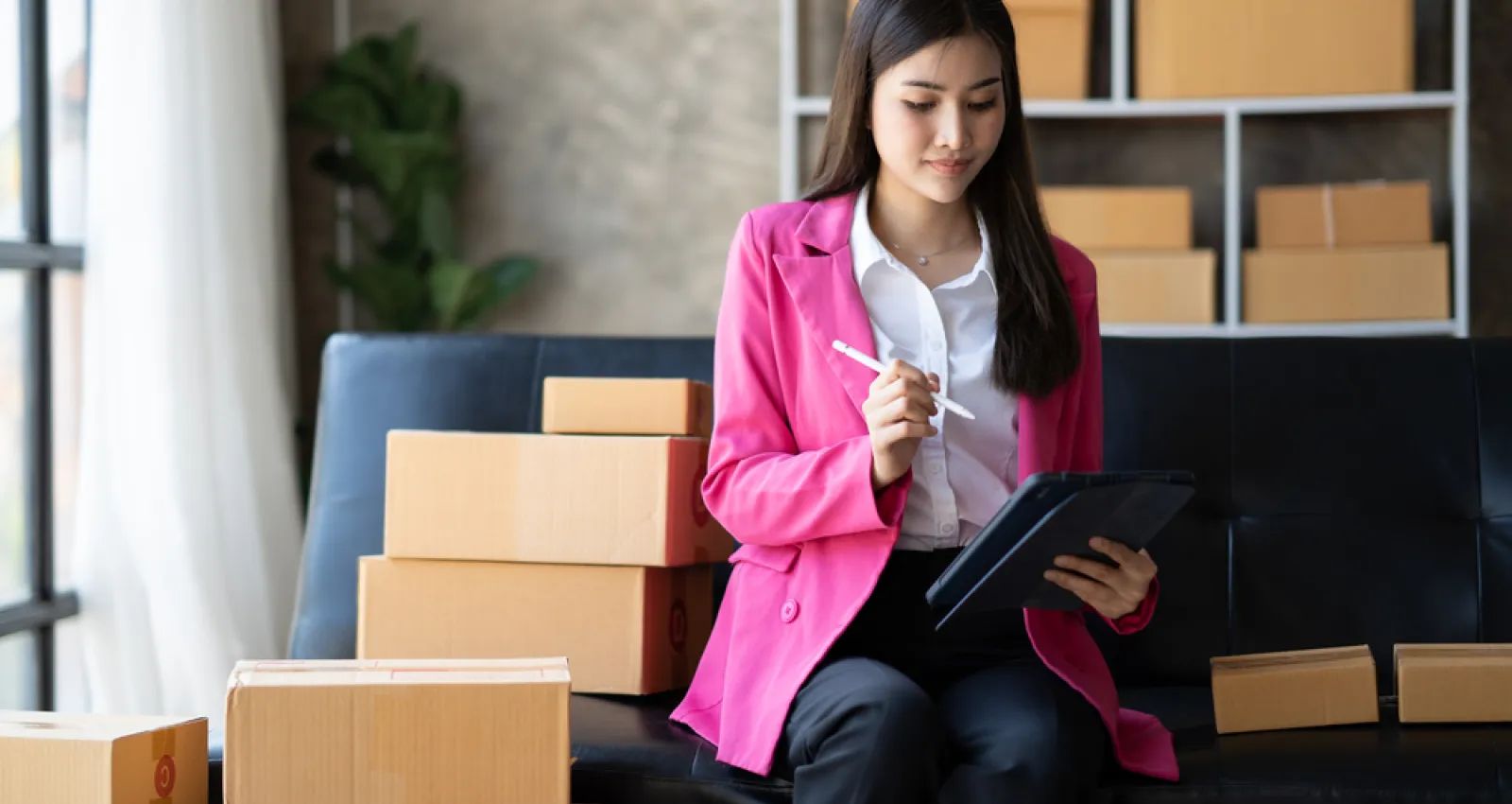 Foto de una mujer con blazer rosado con cajas al fondo
