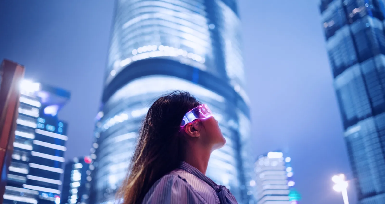Foto de una mujer con gafas tecnológicas y un fondo de ciudad