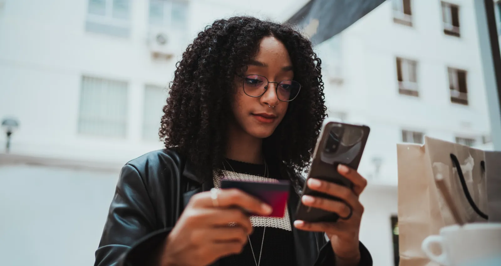 Foto de una mujer con un celular en la mano y una billetera en la otra