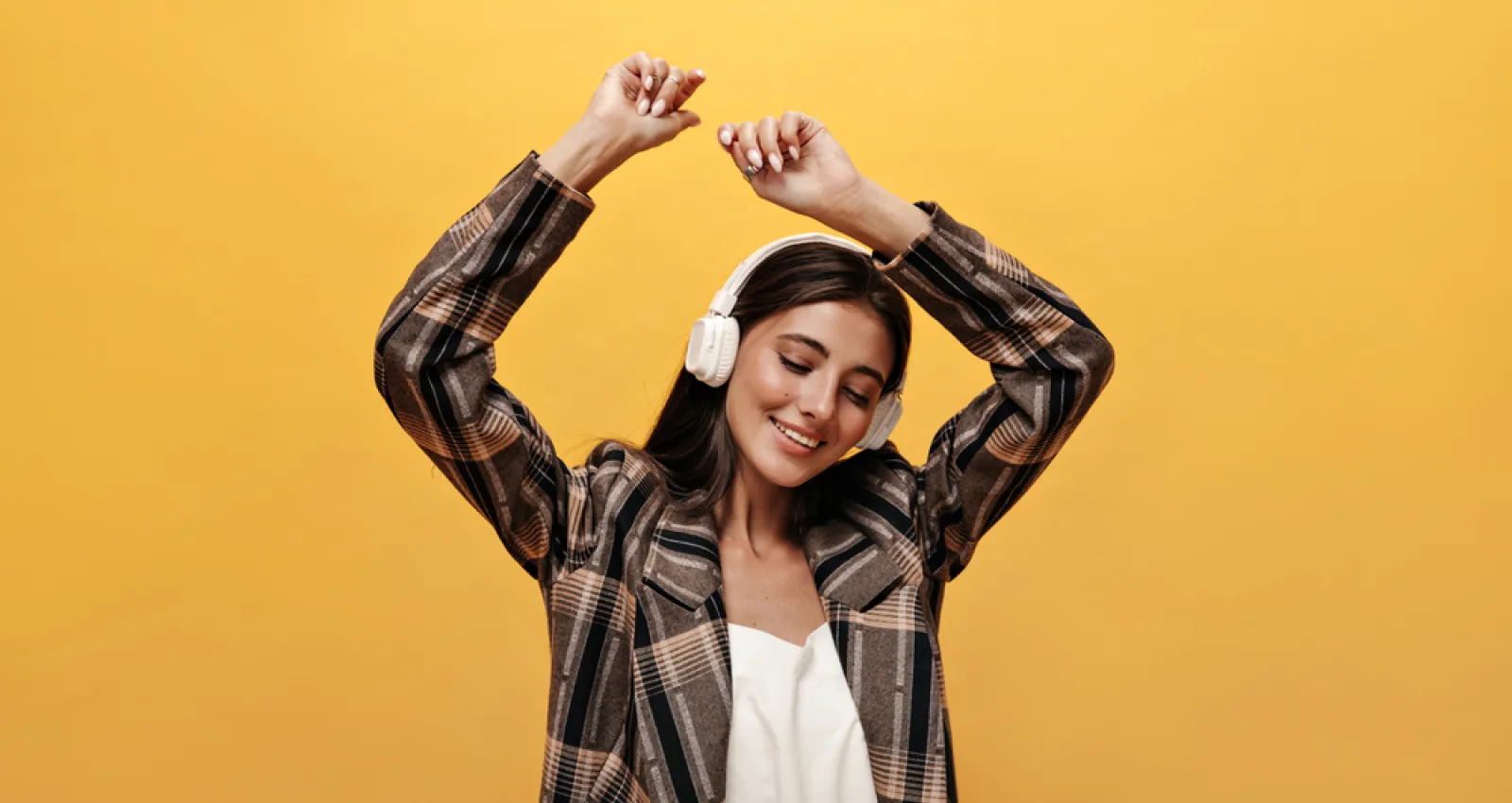 Foto de una mujer escuchando música con un fondo amarillo