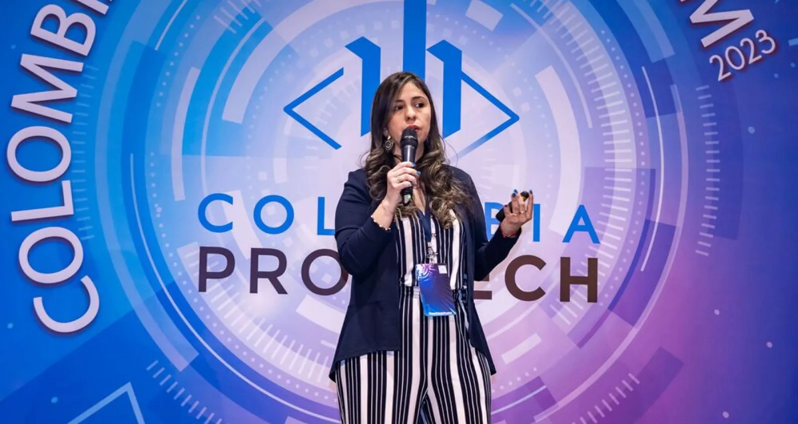 Foto de una mujer exponiendo frente a un logo azul Colombia protech 2024
