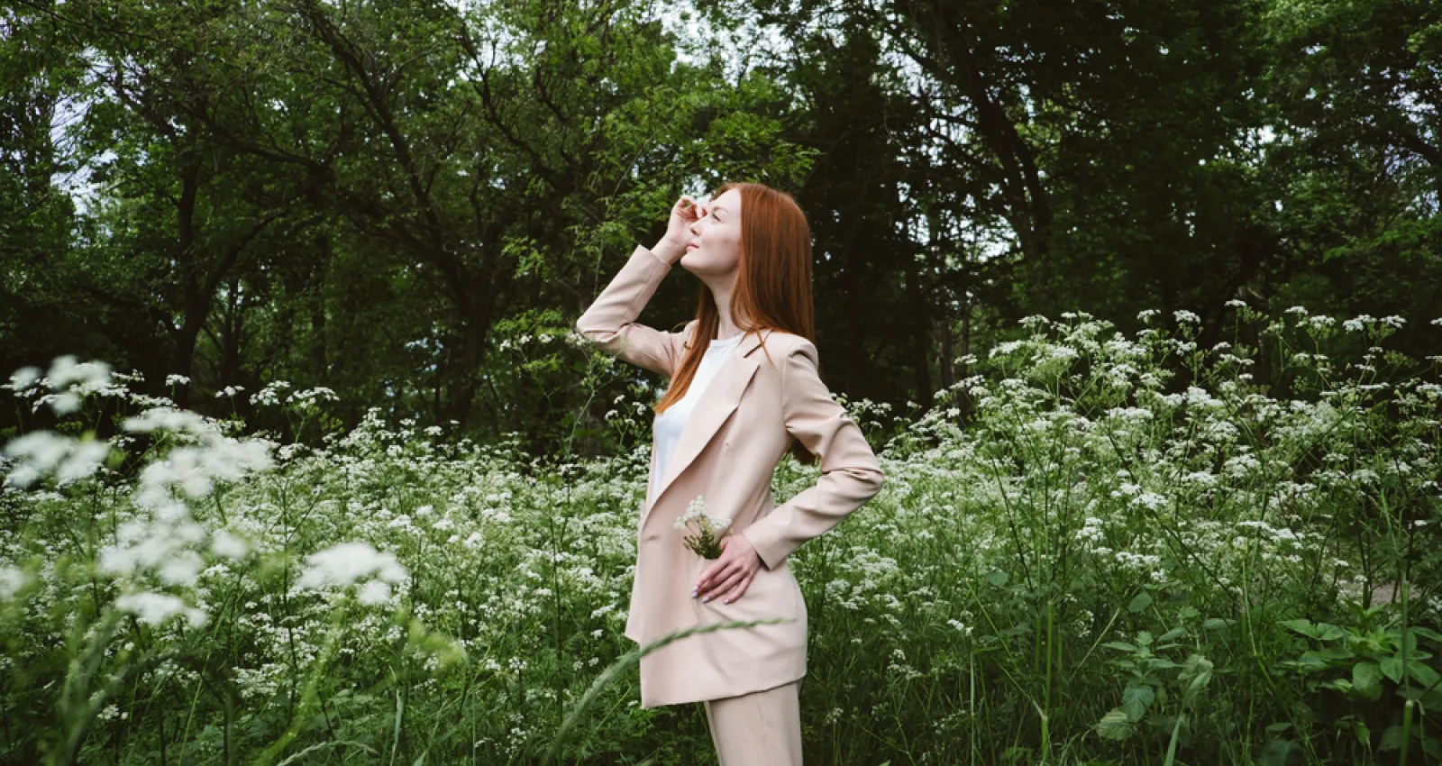 Foto de una mujer mirando hacía el cielo con un campo de flores en la espalda