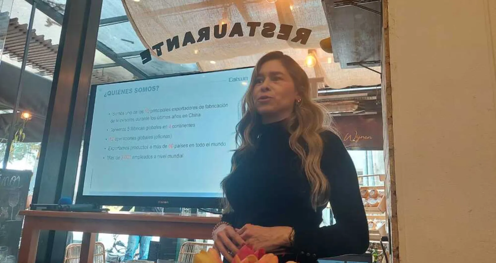 Foto de una mujer presentando frente a un televisor