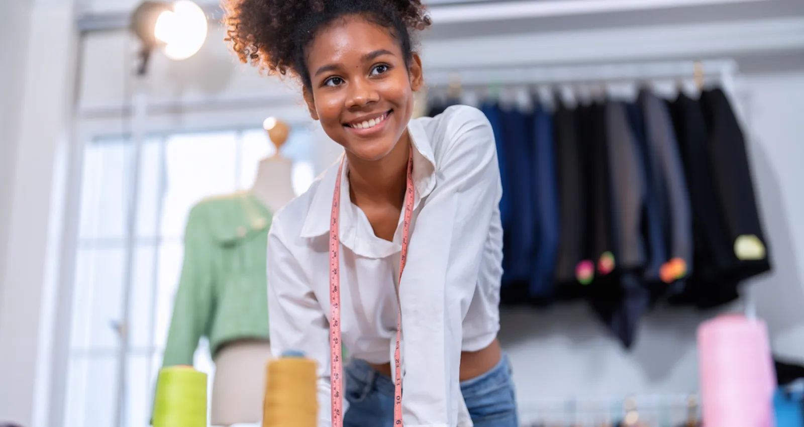 Foto de una mujer sonriendo a la cámara y de fondo unos vestidos