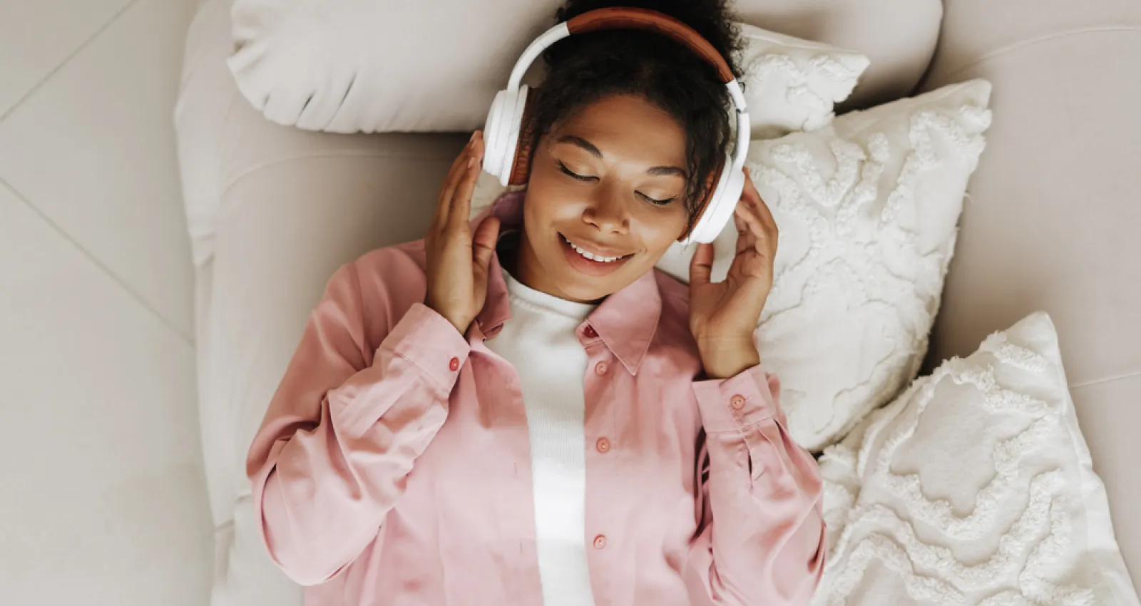 Foto de una mujer tocandose los oidos mientras escucha música