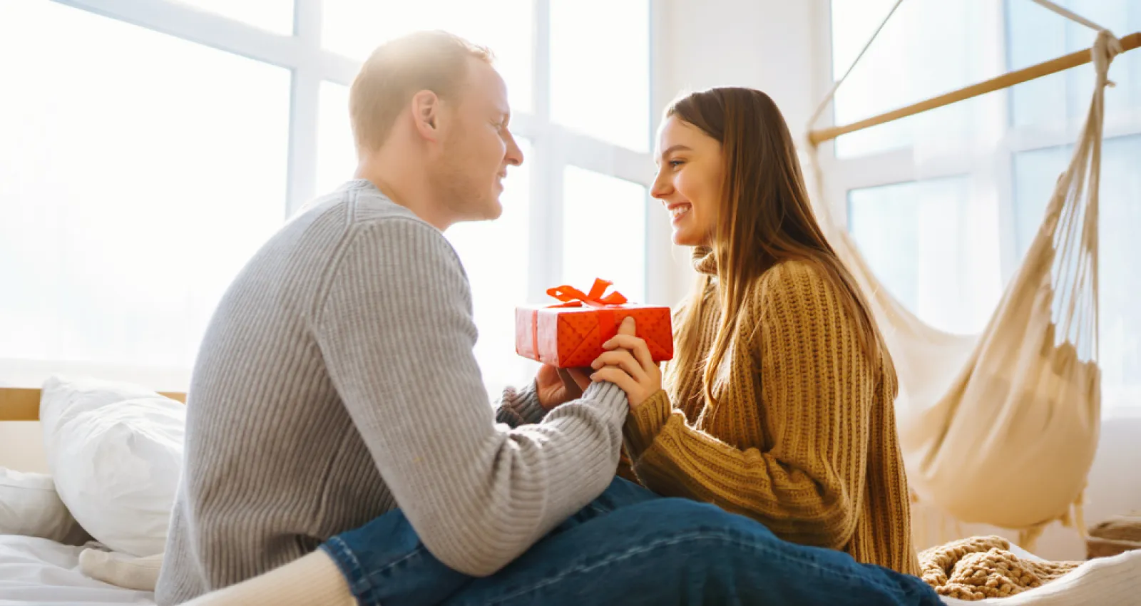 Foto de una pareja mirandose a los ojos con un regalo en sus mano