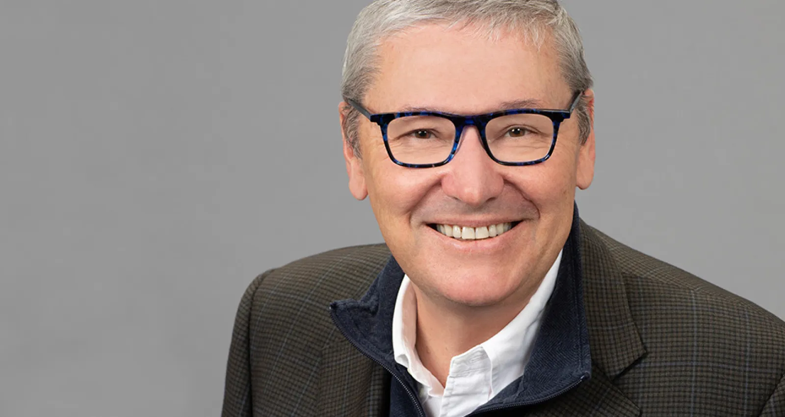 Foto de una persona adulta con gafas negras y canas mirando a la cámara