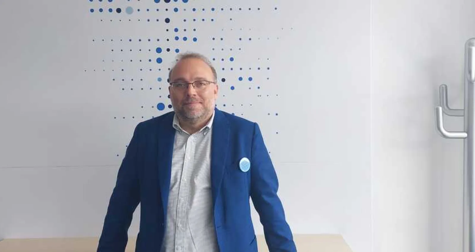 Foto de una persona con brazel y camisa azul mirando a la cámara