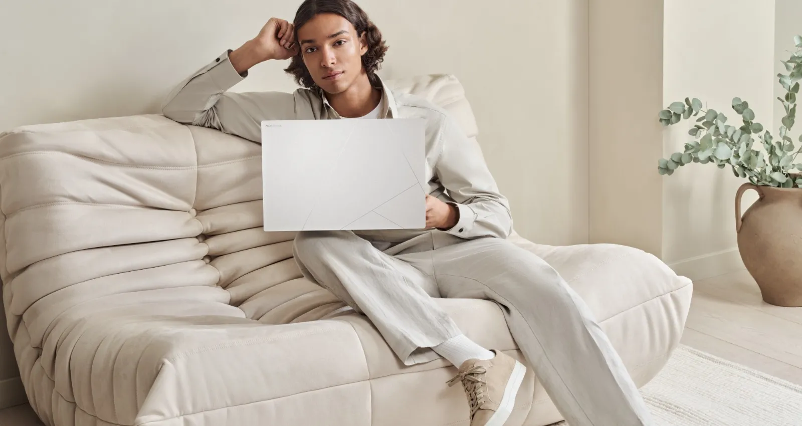 Foto de una persona con una computadora asus blanca sobre un sofa