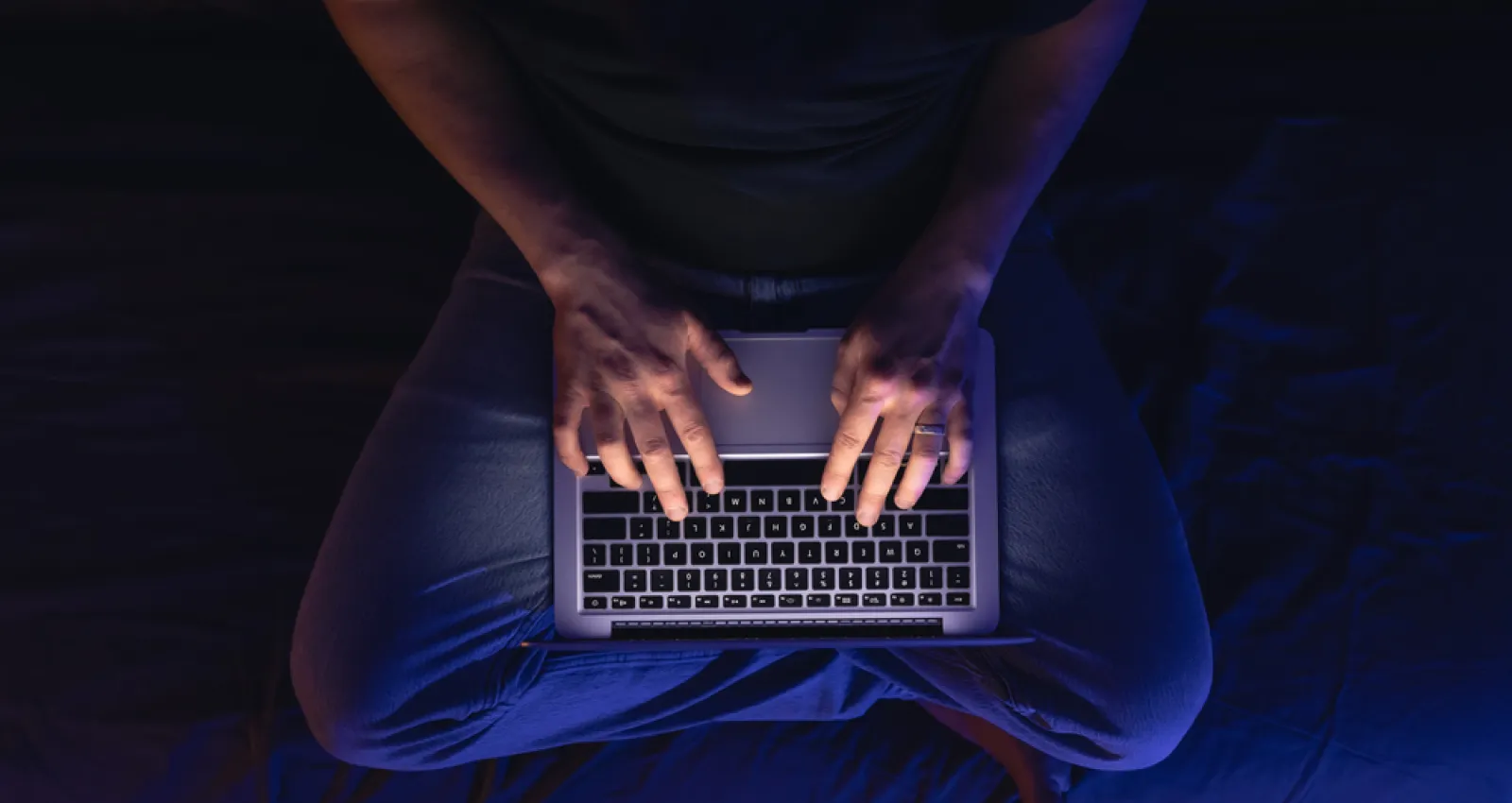 Foto de una persona escribiendo sobre un computador sobre las piernas